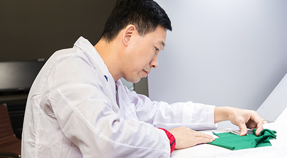 A worker is comparing the lab dips with the color standard in professional light box